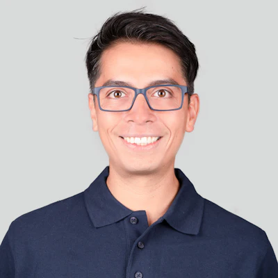 Smiling professional wearing blue polo shirt and rectangular glasses