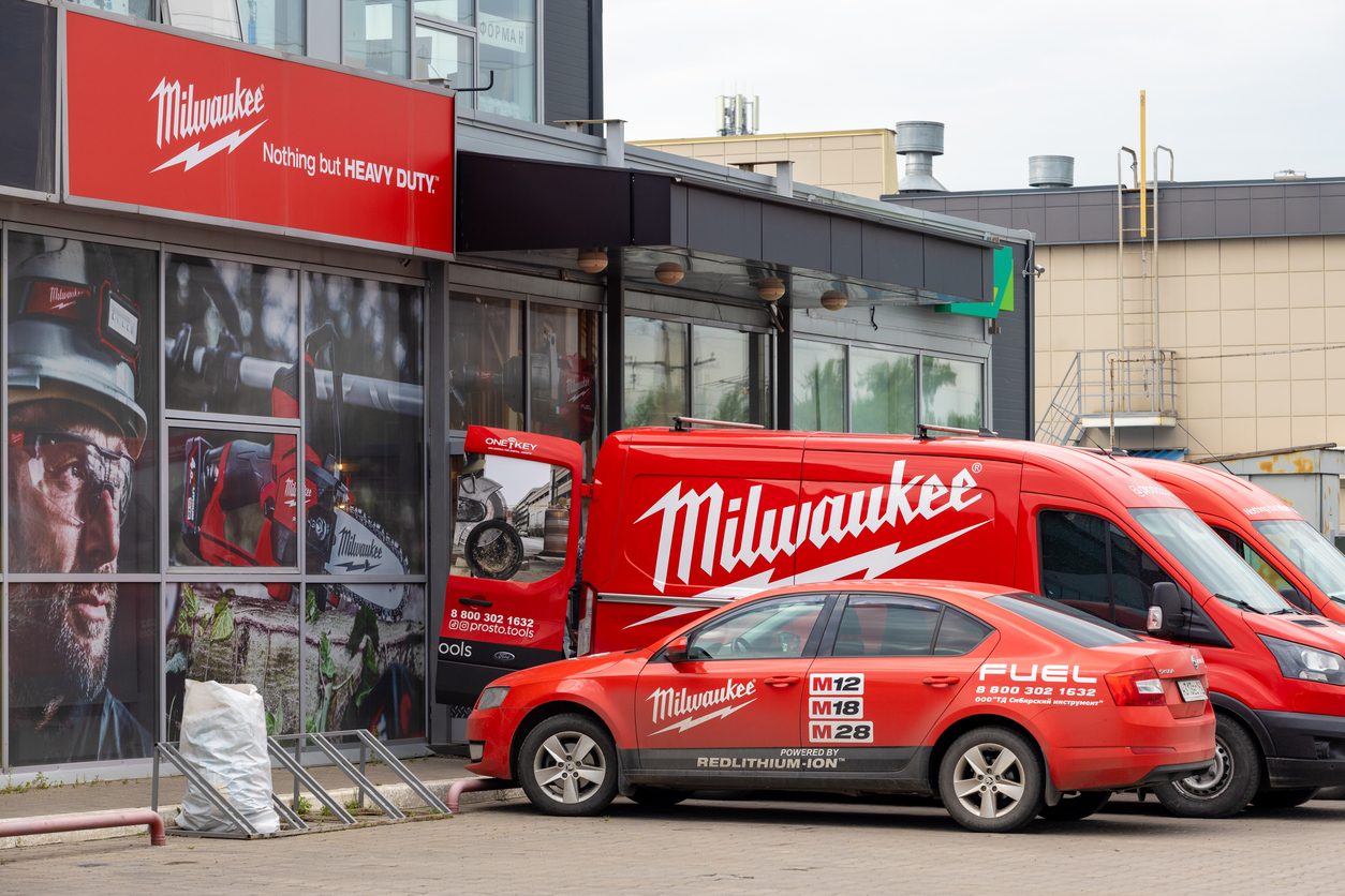 Milwaukee Tools storefront with red branded van and car parked outside industrial building