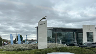 Jaguar car dealership with silver car, glass showroom, and cloudy sky