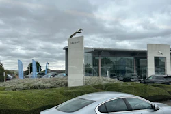 Jaguar car dealership with silver car, glass showroom, and cloudy sky