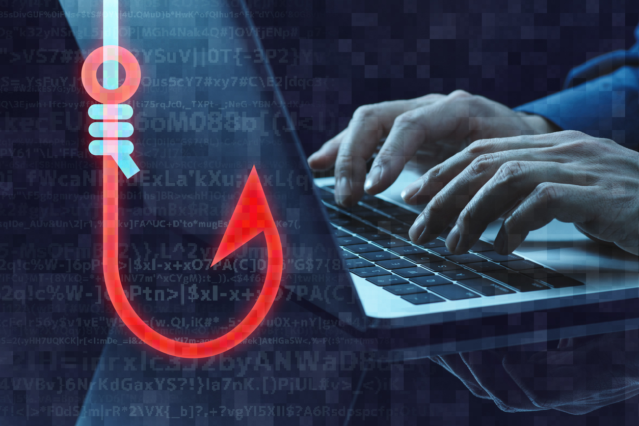 Cybersecurity concept showing hands typing on laptop with digital phishing hook