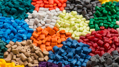 Colorful polymer pellets in blue, red, green, yellow, orange, and gray arranged in clusters