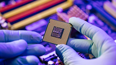 Gloved hands carefully holding a computer microprocessor chip in a purple-tinted tech environment