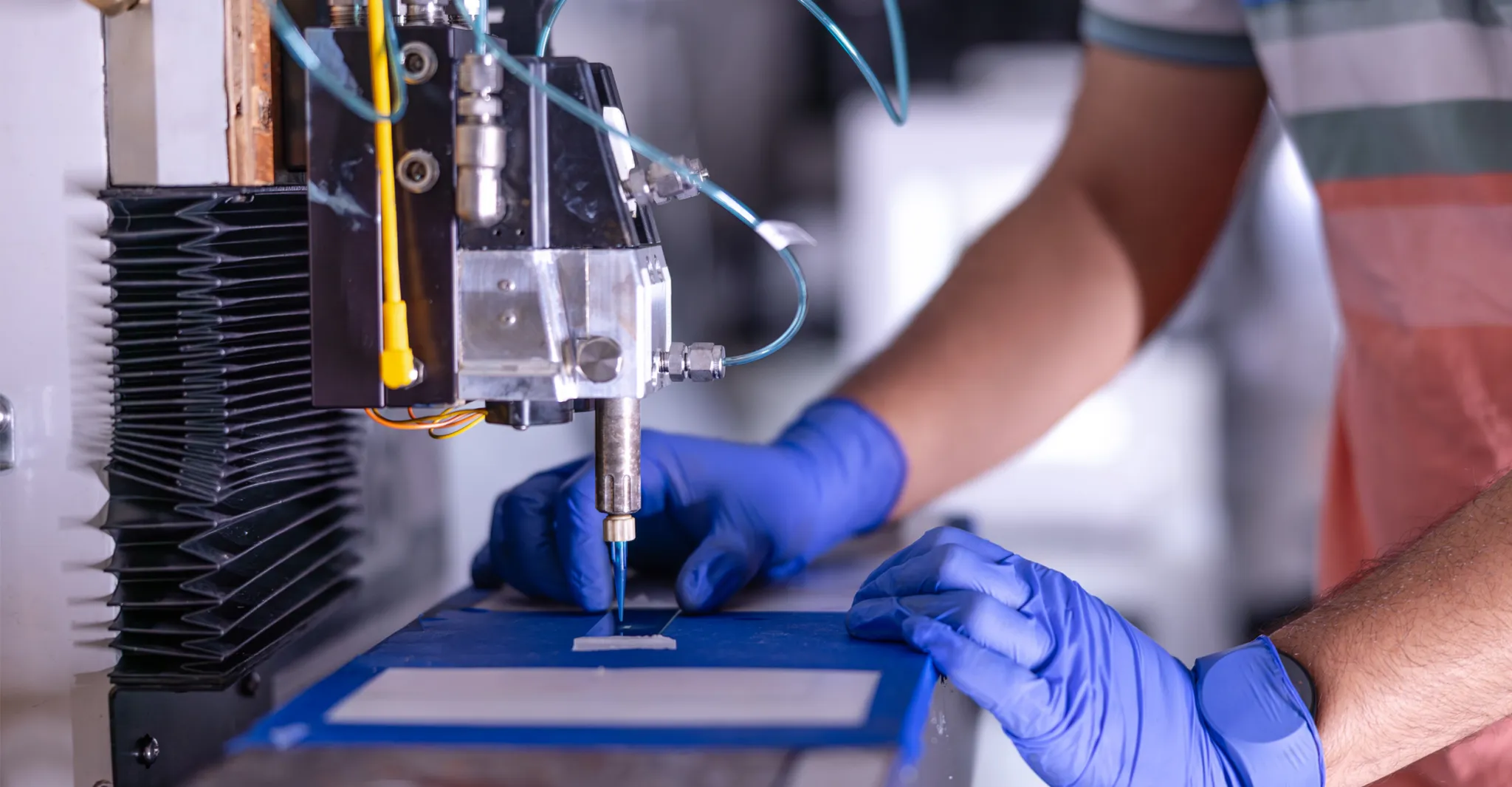 Precision robotic machine with blue-gloved hands performing scientific or manufacturing process