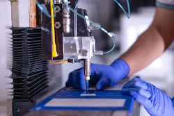 Precision robotic machine with blue-gloved hands performing scientific or manufacturing process
