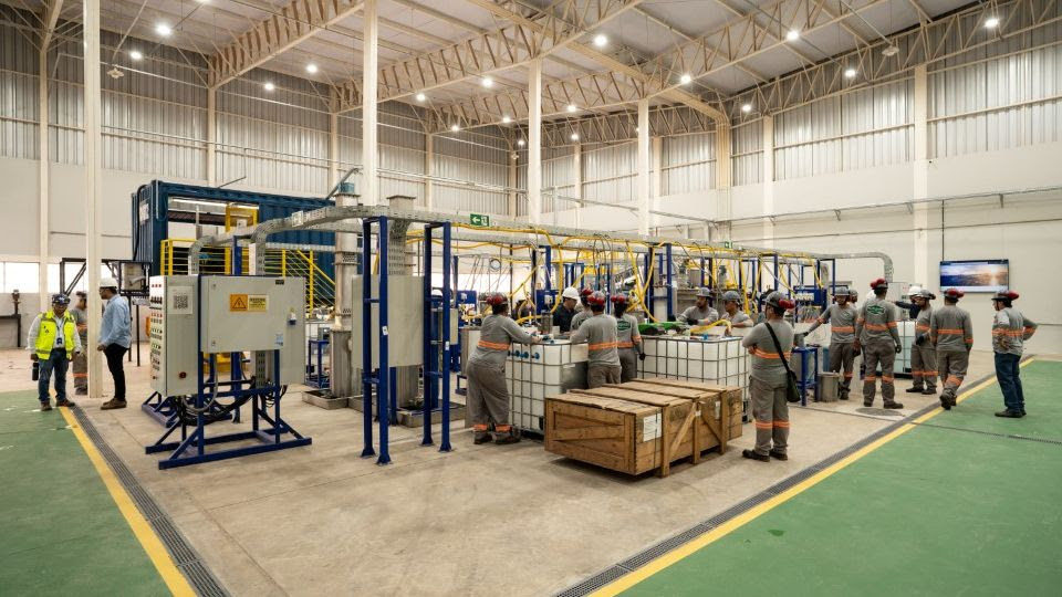 Industrial facility with workers operating machinery and equipment on green floor