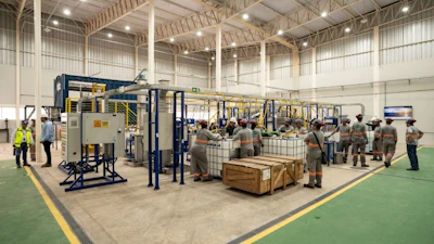 Industrial facility with workers operating machinery and equipment on green floor
