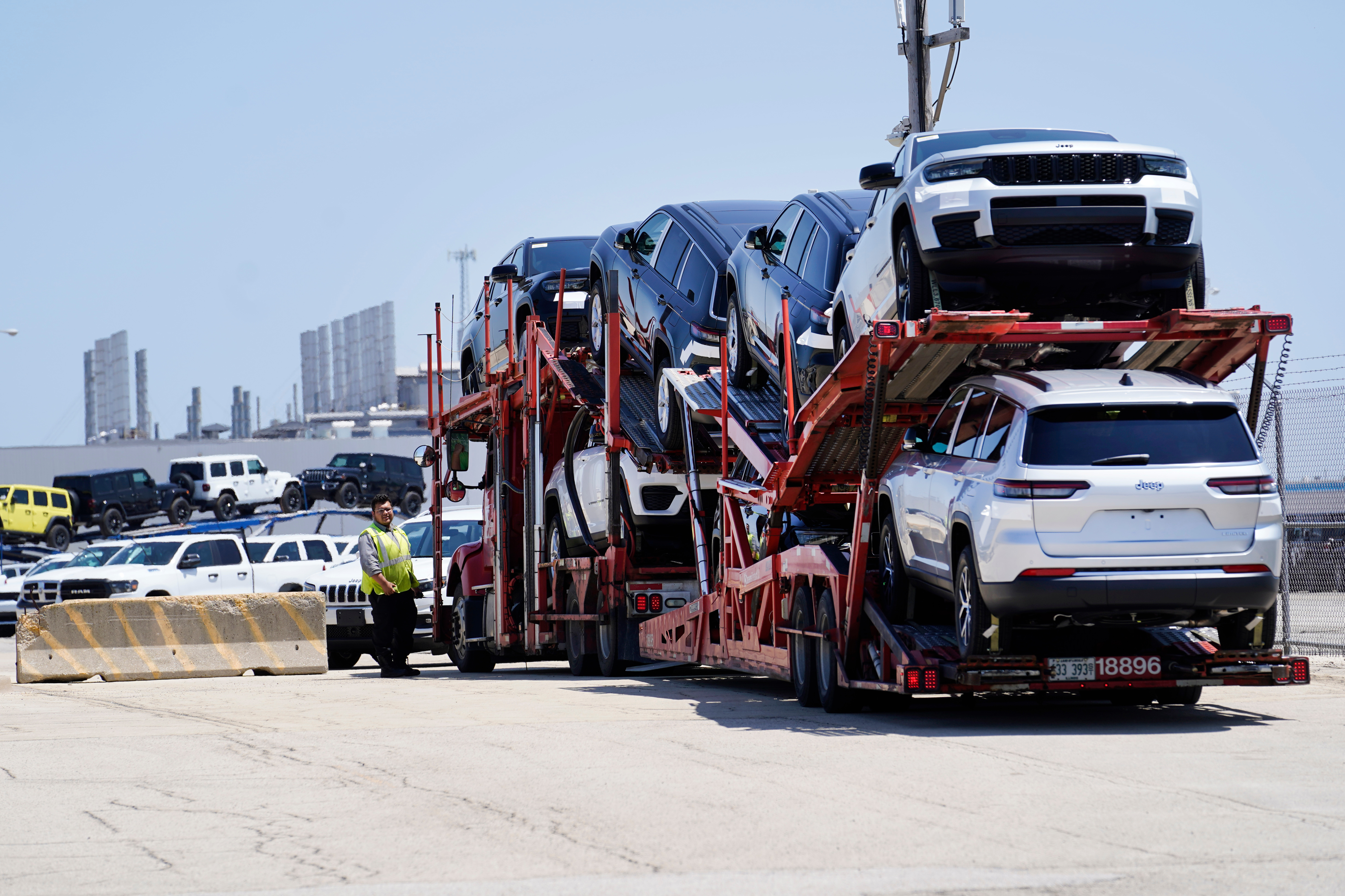 Car carrier trailer loaded with white SUVs at transportation facility