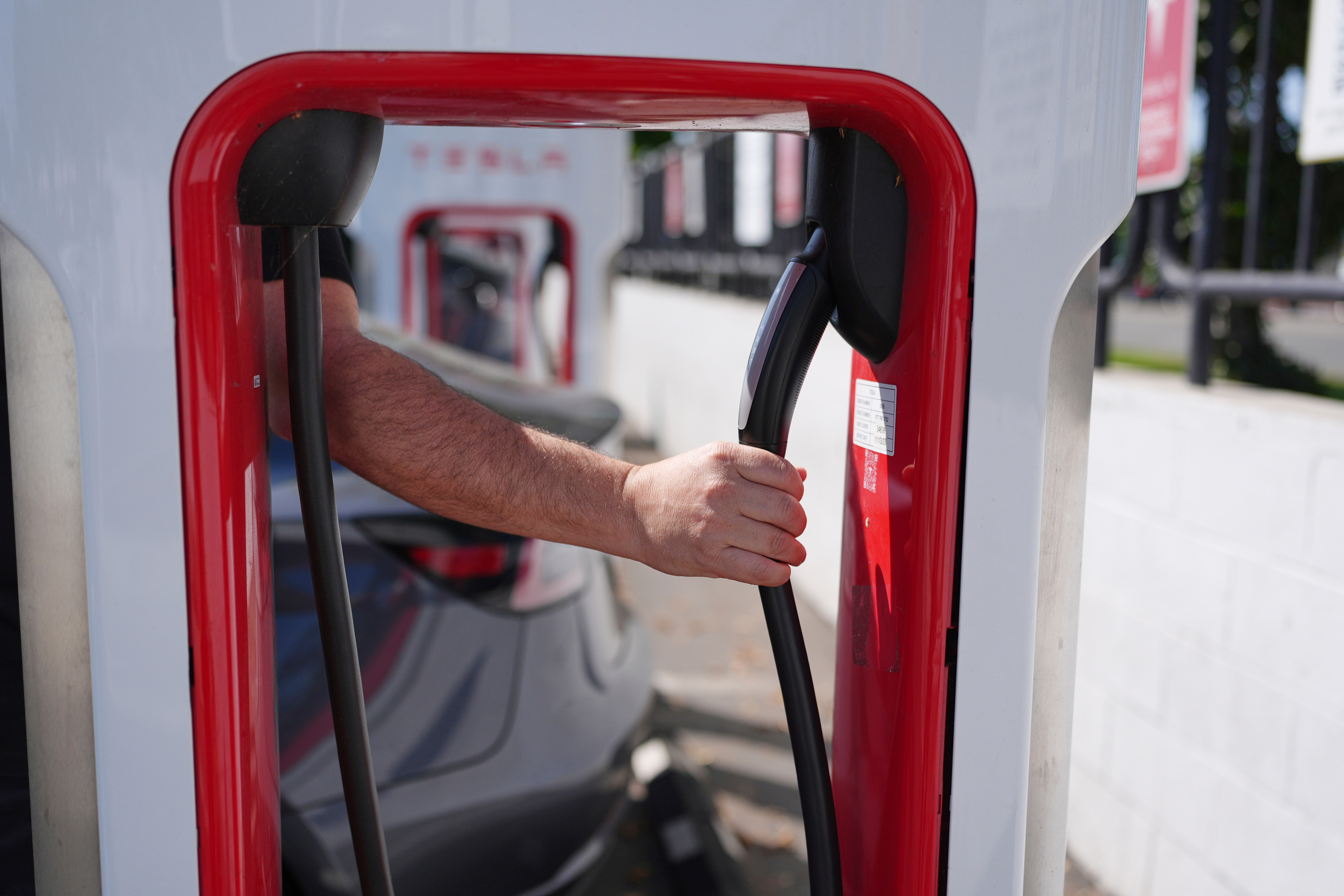 Red gas pump with hand holding black fuel nozzle at fueling station