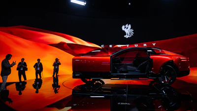Red luxury concept car on stage with dramatic lighting and silhouetted figures