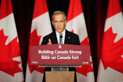 Canadian government official speaking at podium with Canadian flags in background