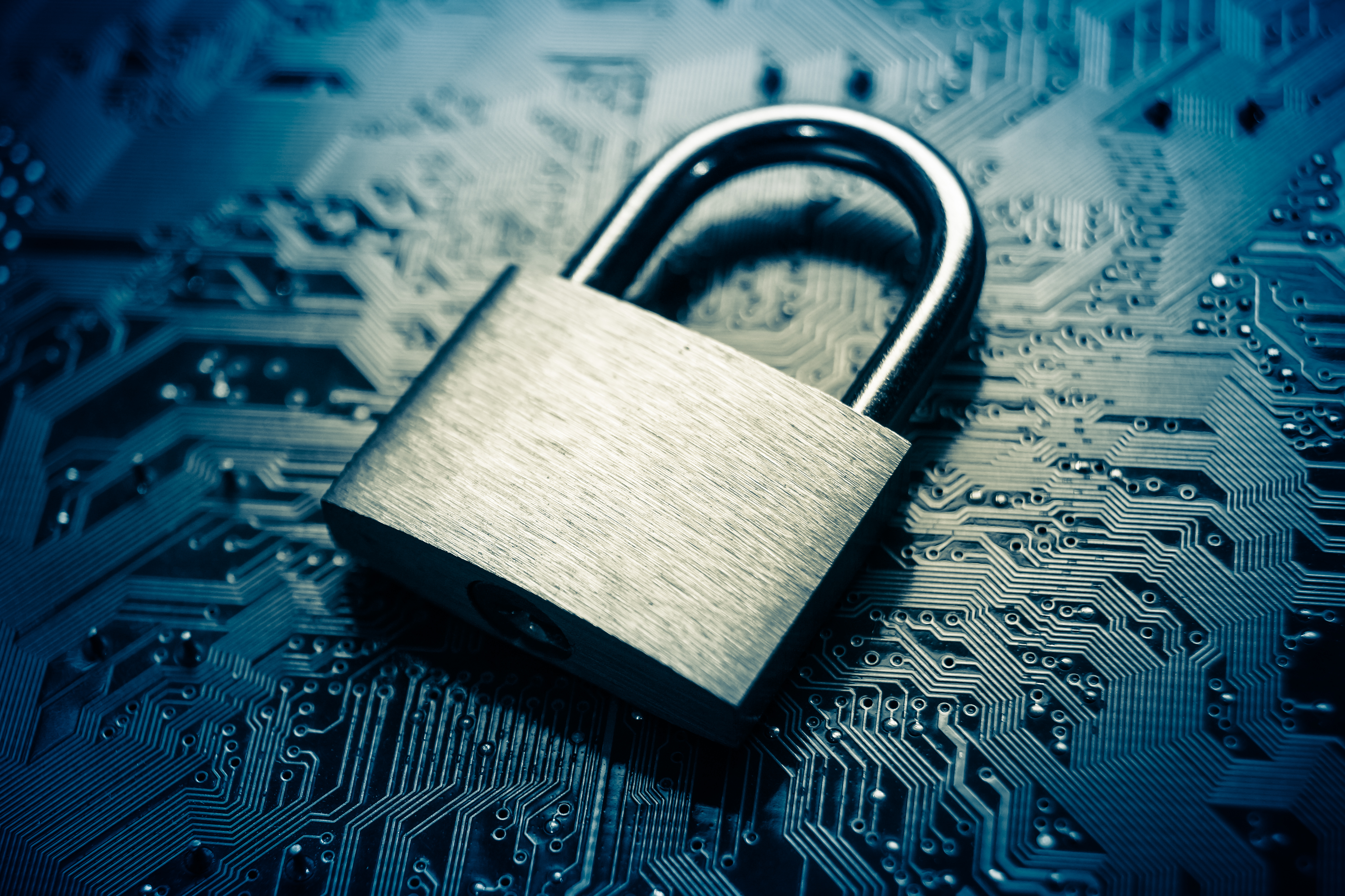 Metallic padlock resting on blue circuit board, symbolizing digital security