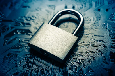Metallic padlock resting on blue circuit board, symbolizing digital security