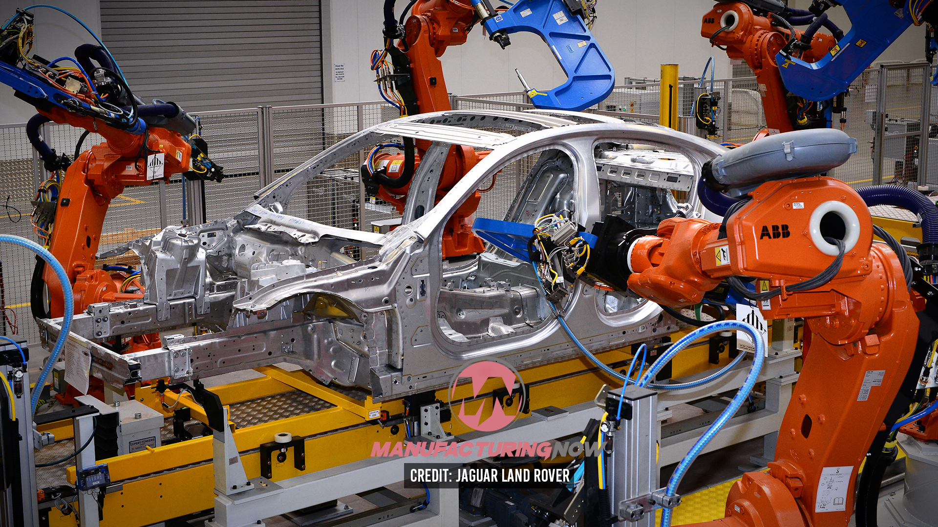 Robotic arms assembling car body frame in automotive manufacturing facility