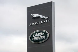 Jaguar Land Rover corporate sign with logos on tall black monolith against cloudy sky
