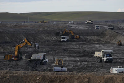 Construction site with excavators and dump trucks working in a rocky, grey landscape