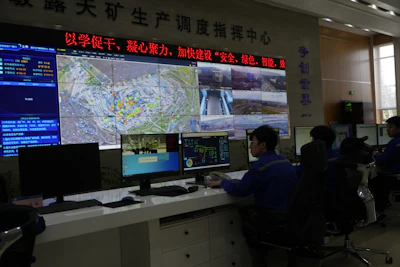 Mining production control center with data screens and operators monitoring multiple displays
