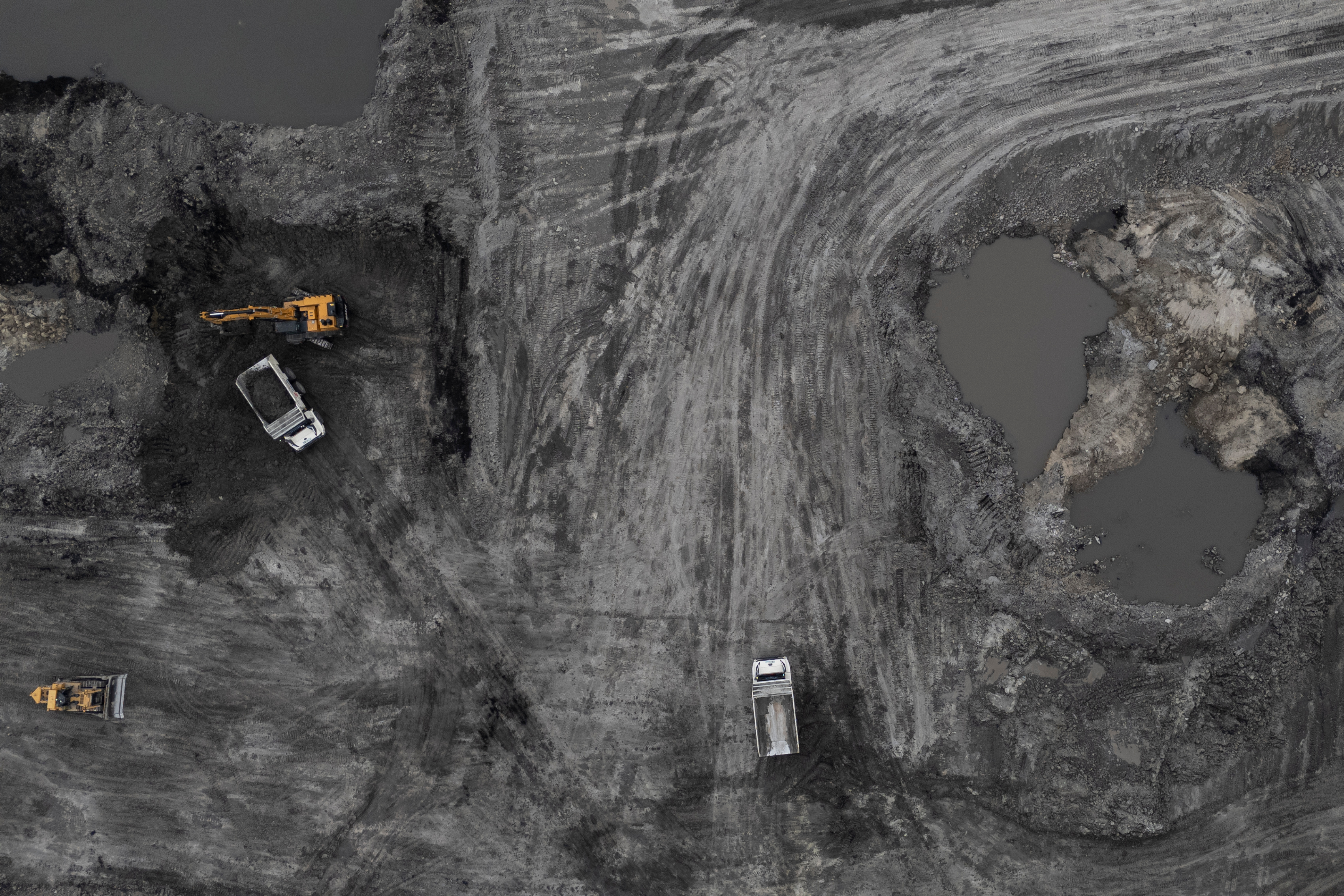 Aerial view of mining excavation site with construction vehicles on gray terrain