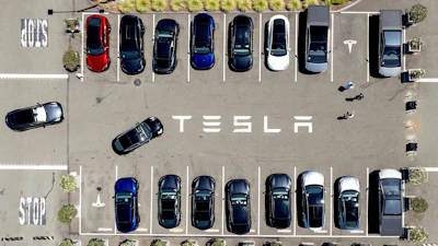 Aerial view of Tesla parking lot with multiple electric vehicles in parking spaces