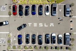 Aerial view of Tesla parking lot with multiple electric vehicles in parking spaces