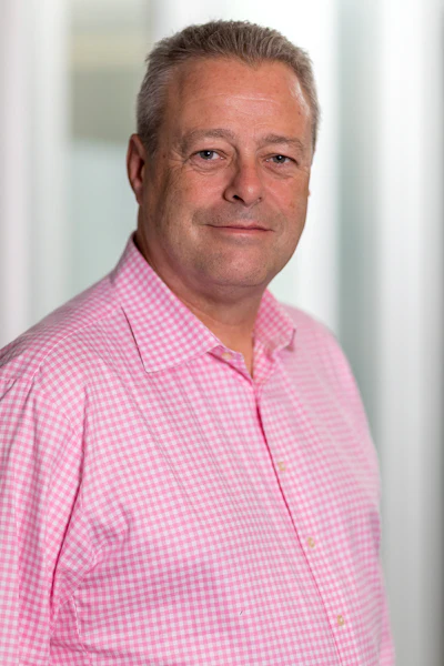 Middle-aged professional in pink gingham shirt against blurred white background