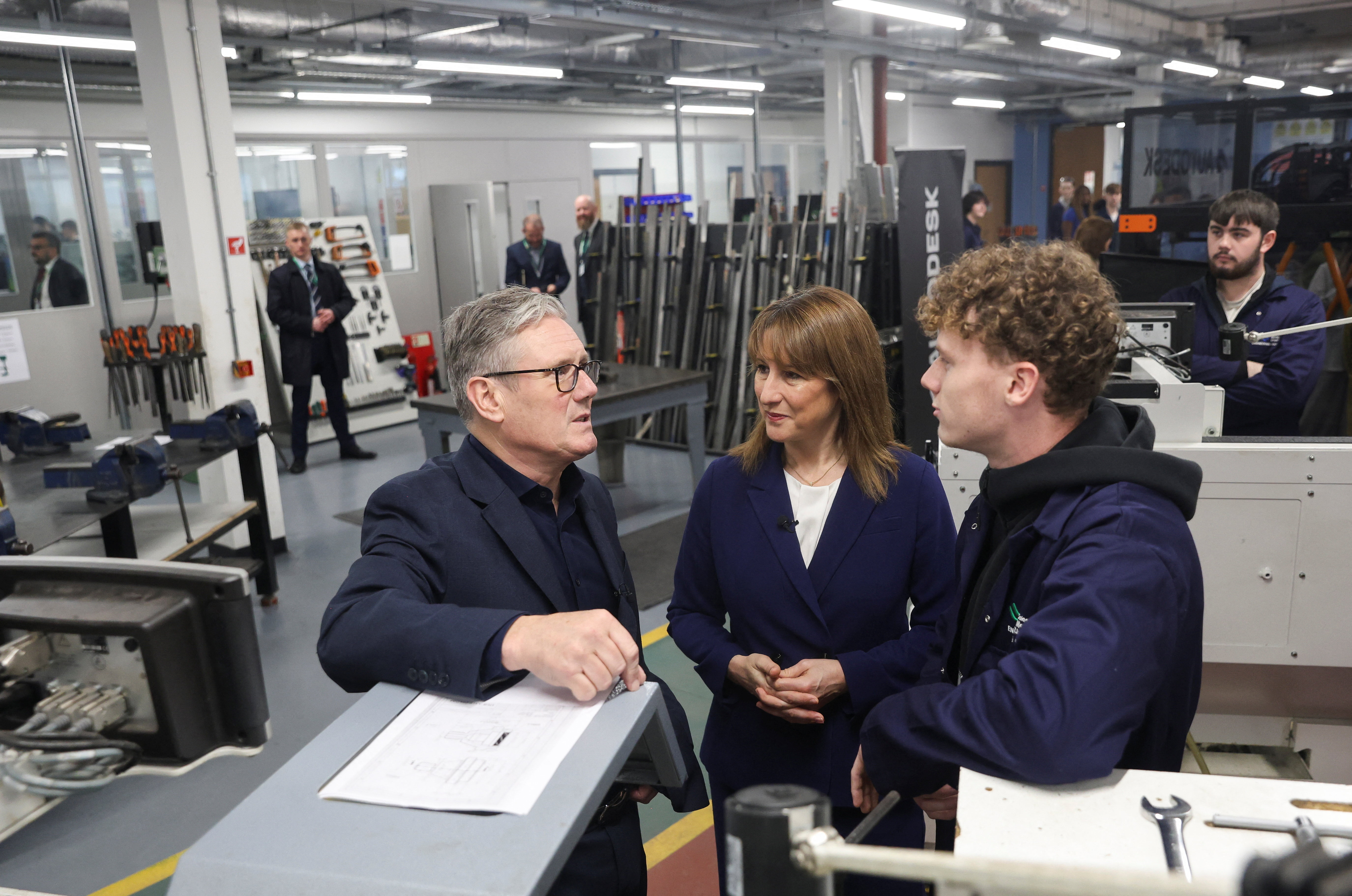 Business professionals discussing project in industrial workshop with machinery