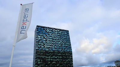 Nexperia corporate flag and modern black-blue geometric building on grassy hill