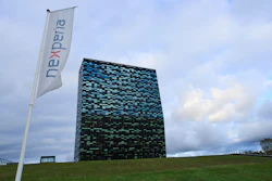 Nexperia corporate flag and modern black-blue geometric building on grassy hill