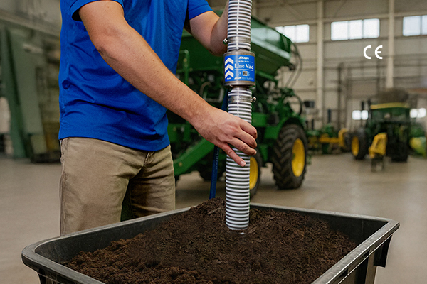 Agricultural technician testing soil sample in industrial facility near green farming equipment
