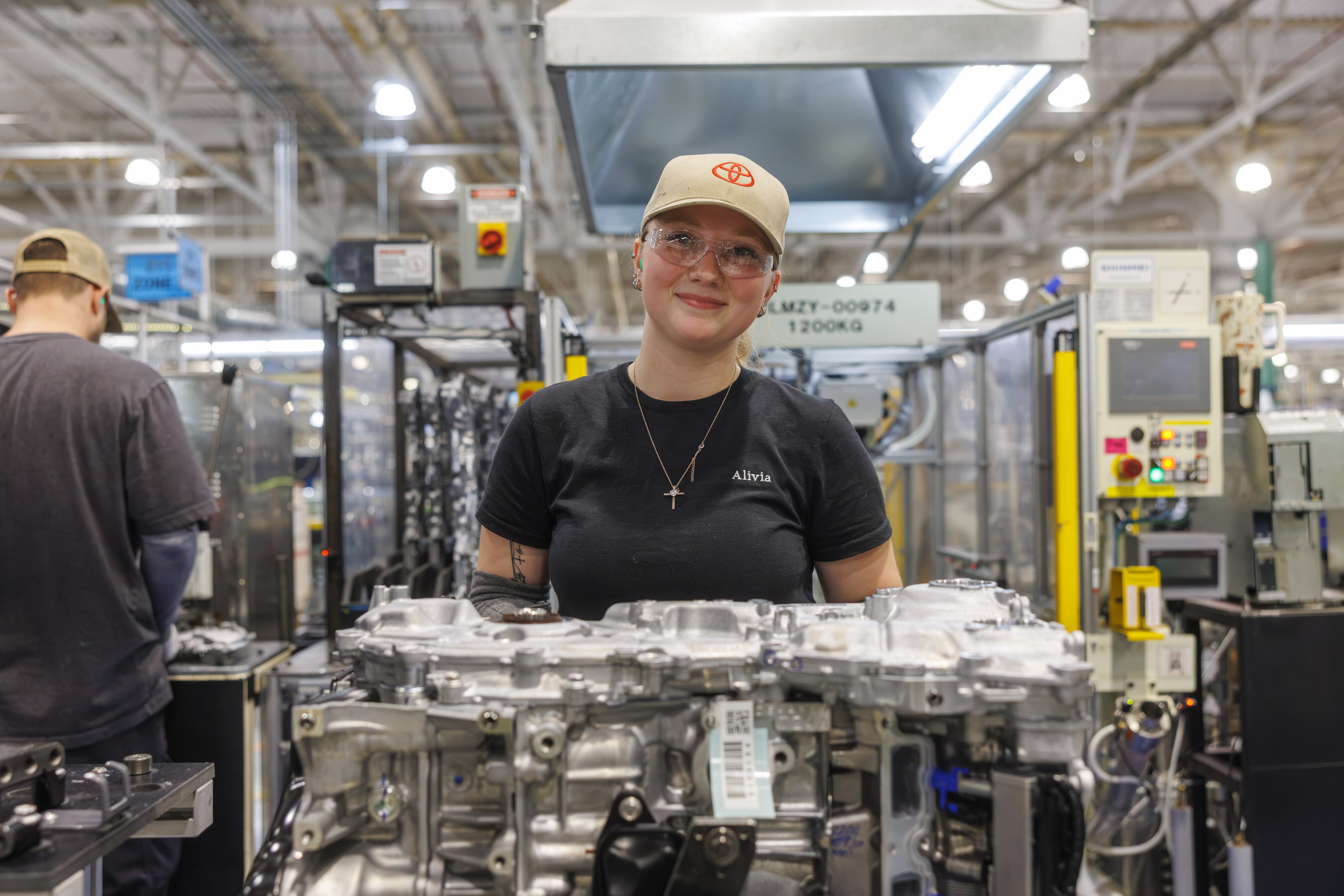 Factory worker standing near automotive engine components in manufacturing facility