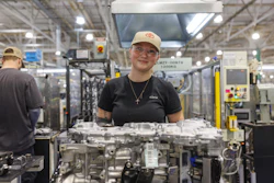 Factory worker standing near automotive engine components in manufacturing facility