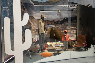 Outdoor retail display with camping gear, mannequins, and mountain landscape backdrop