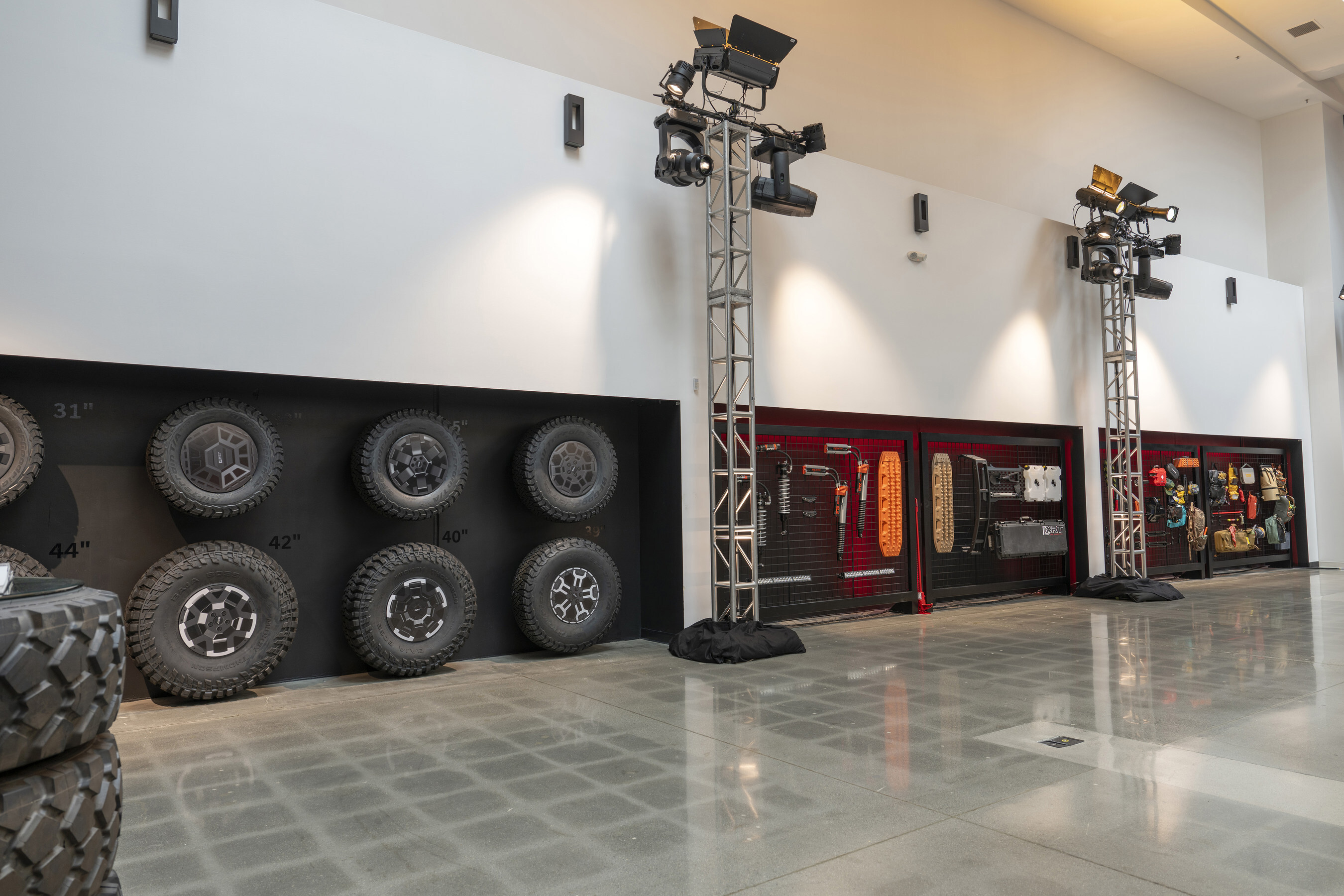 Vehicle showroom with automotive tires, lighting towers, and technical display panels