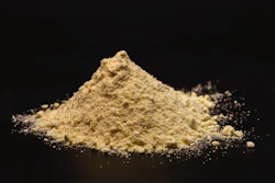 Pile of yellow ground powder with scattered granules on black background