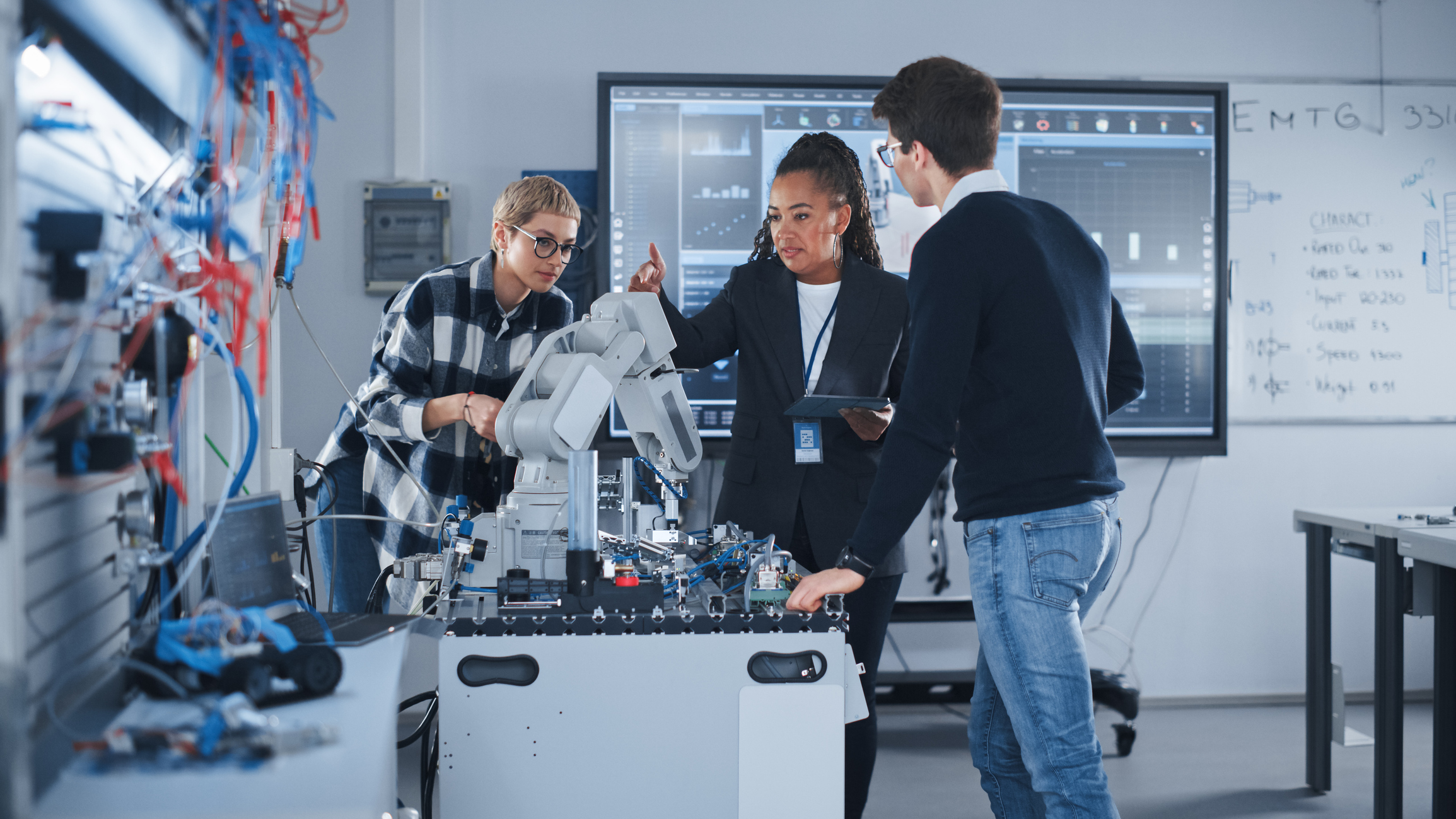 Technical team collaborating around robotic machinery in modern research laboratory