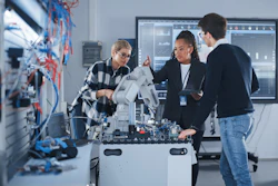 Technical team collaborating around robotic machinery in modern research laboratory
