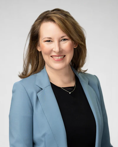 Professional woman smiling in blue blazer against neutral background