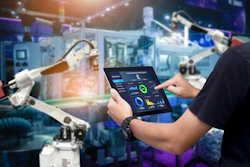 Industrial technician monitoring robotic systems using digital tablet with performance analytics
