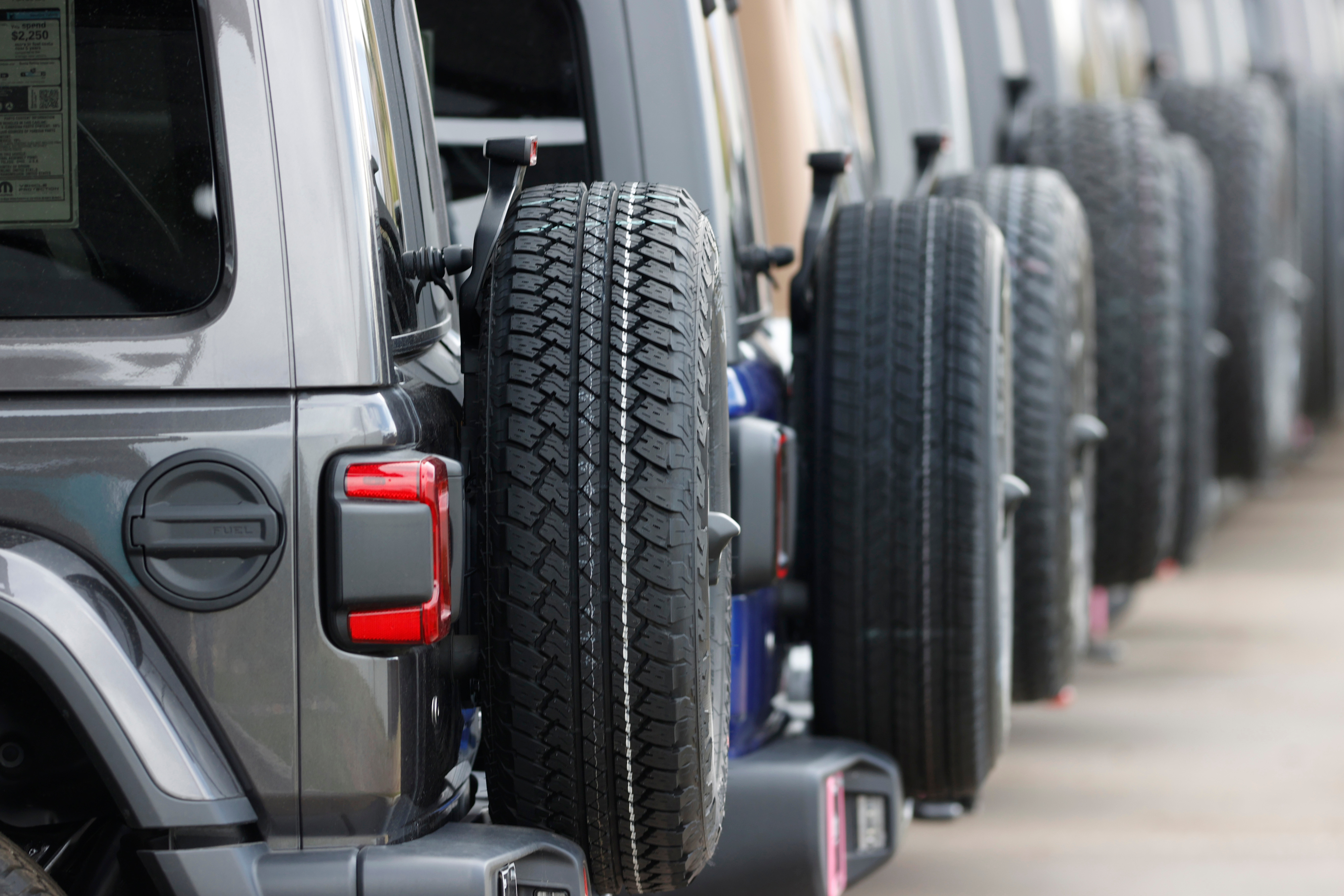 Row of spare tires mounted on the sides of gray SUVs or off-road vehicles