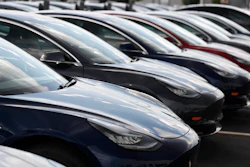 Multiple dark blue Tesla electric vehicles lined up in a parking lot