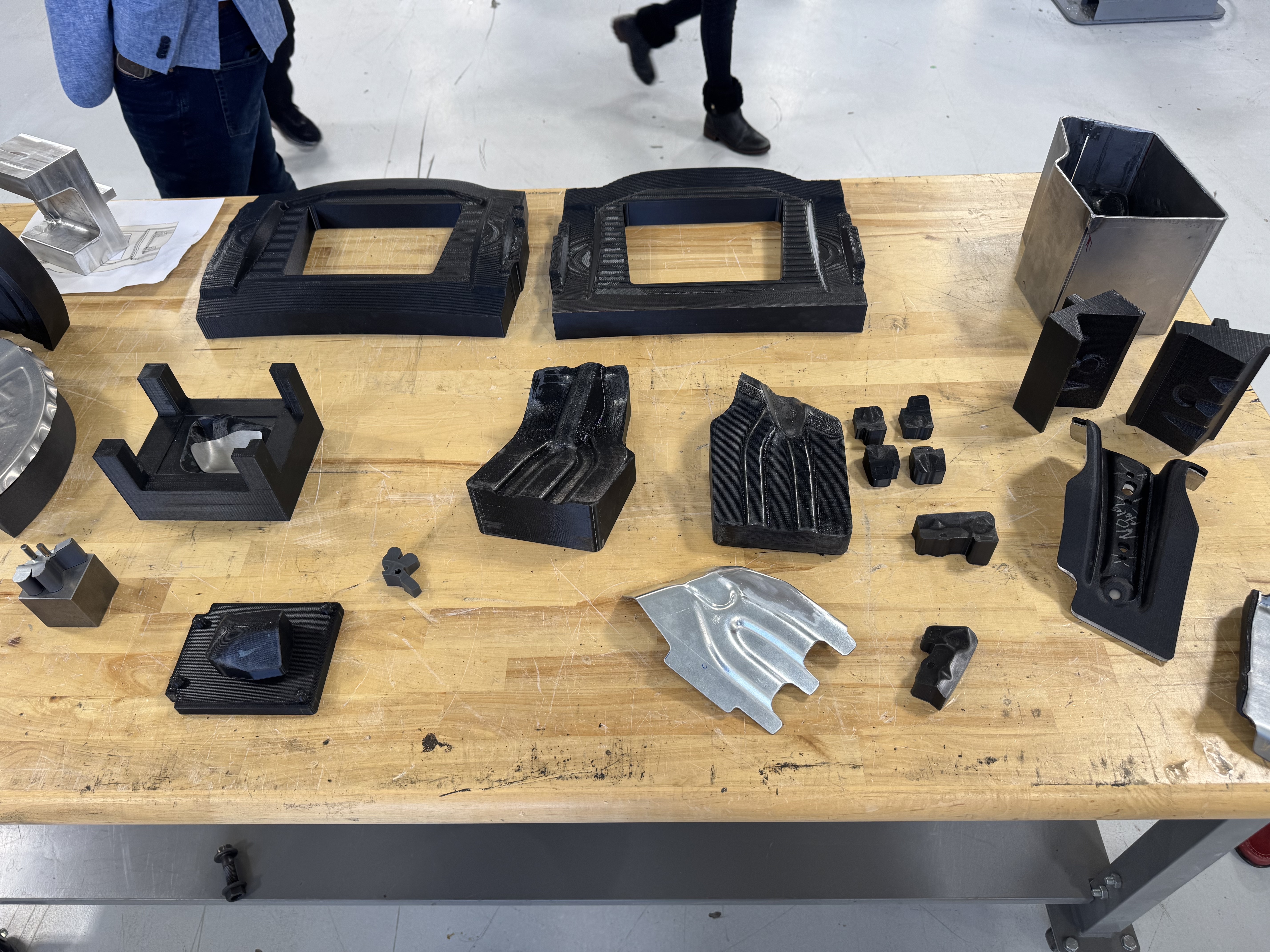 Black industrial molds and metal components arranged on wooden workbench