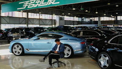 Blue luxury car in showroom with person sitting on office chair