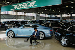 Blue luxury car in showroom with person sitting on office chair