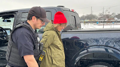 Law enforcement officer assisting person in winter clothing near black truck
