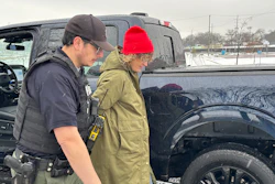 Law enforcement officer assisting person in winter clothing near black truck