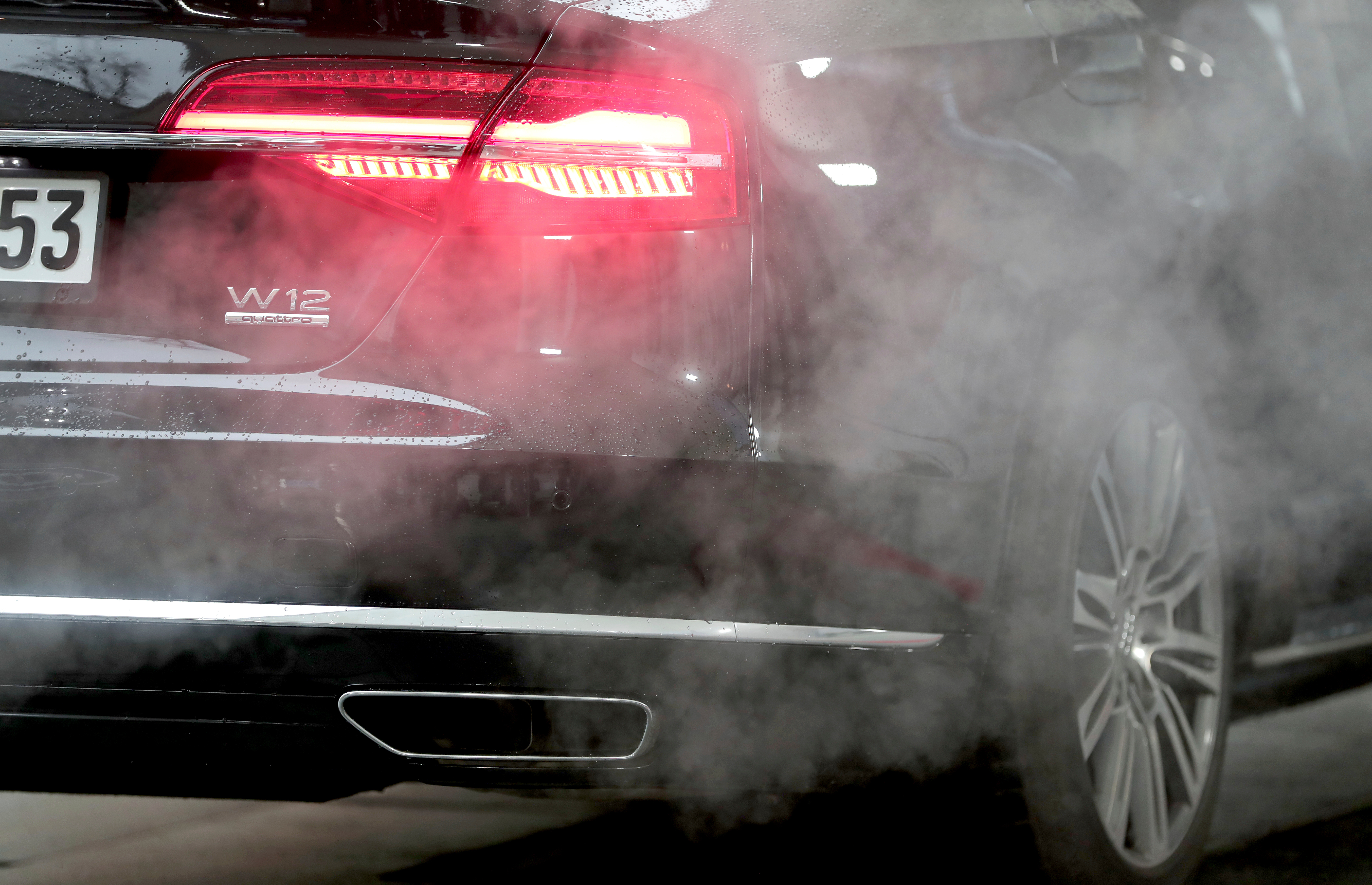 Luxury car taillight emitting red glow with smoke surrounding exhaust