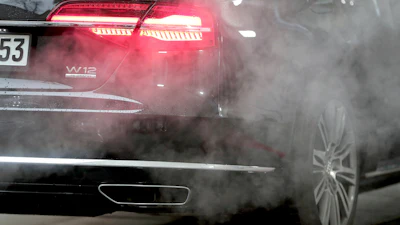 Luxury car taillight emitting red glow with smoke surrounding exhaust