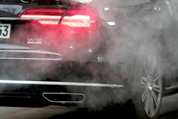 Luxury car taillight emitting red glow with smoke surrounding exhaust