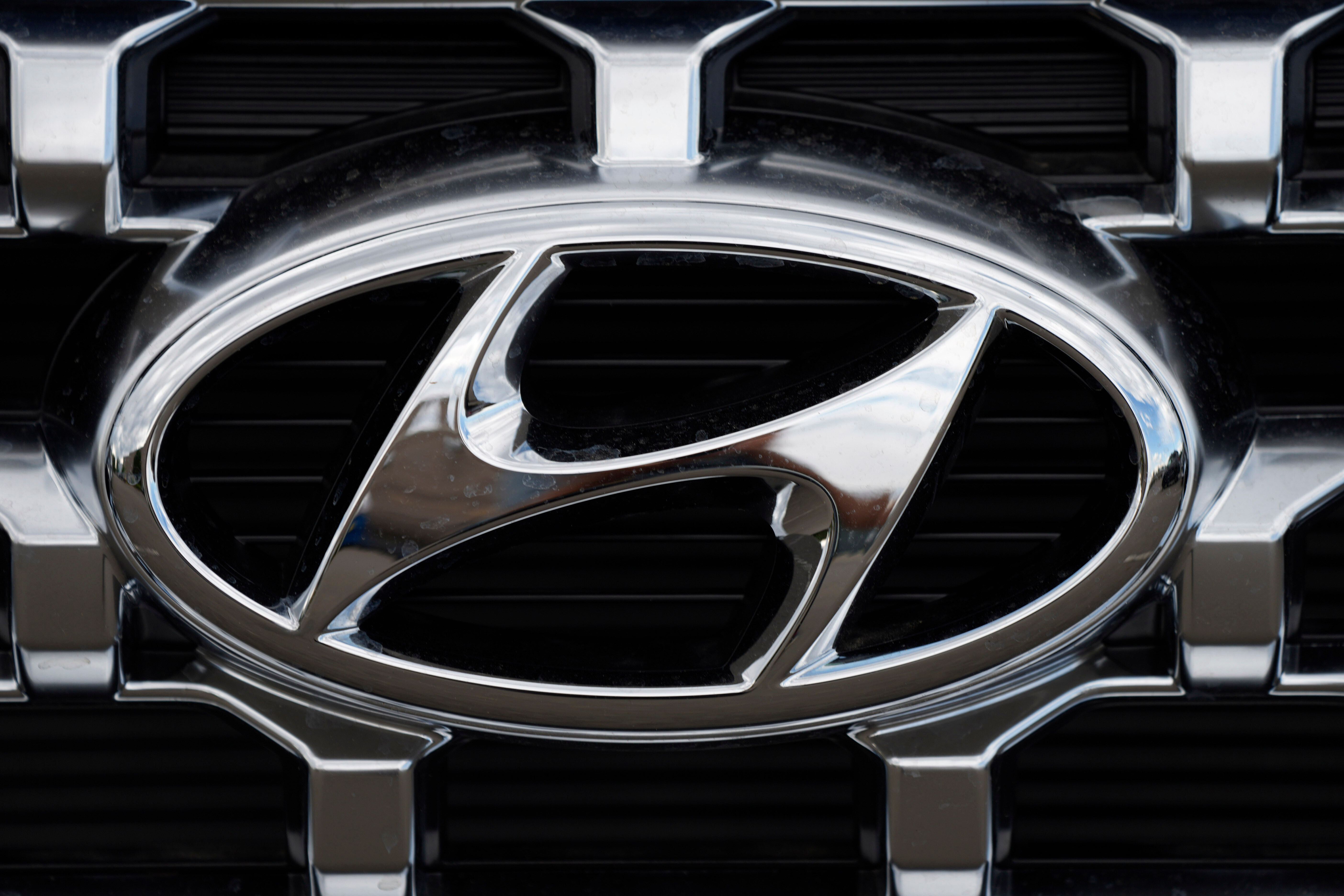 Hyundai chrome logo on vehicle grille with metallic silver and black details