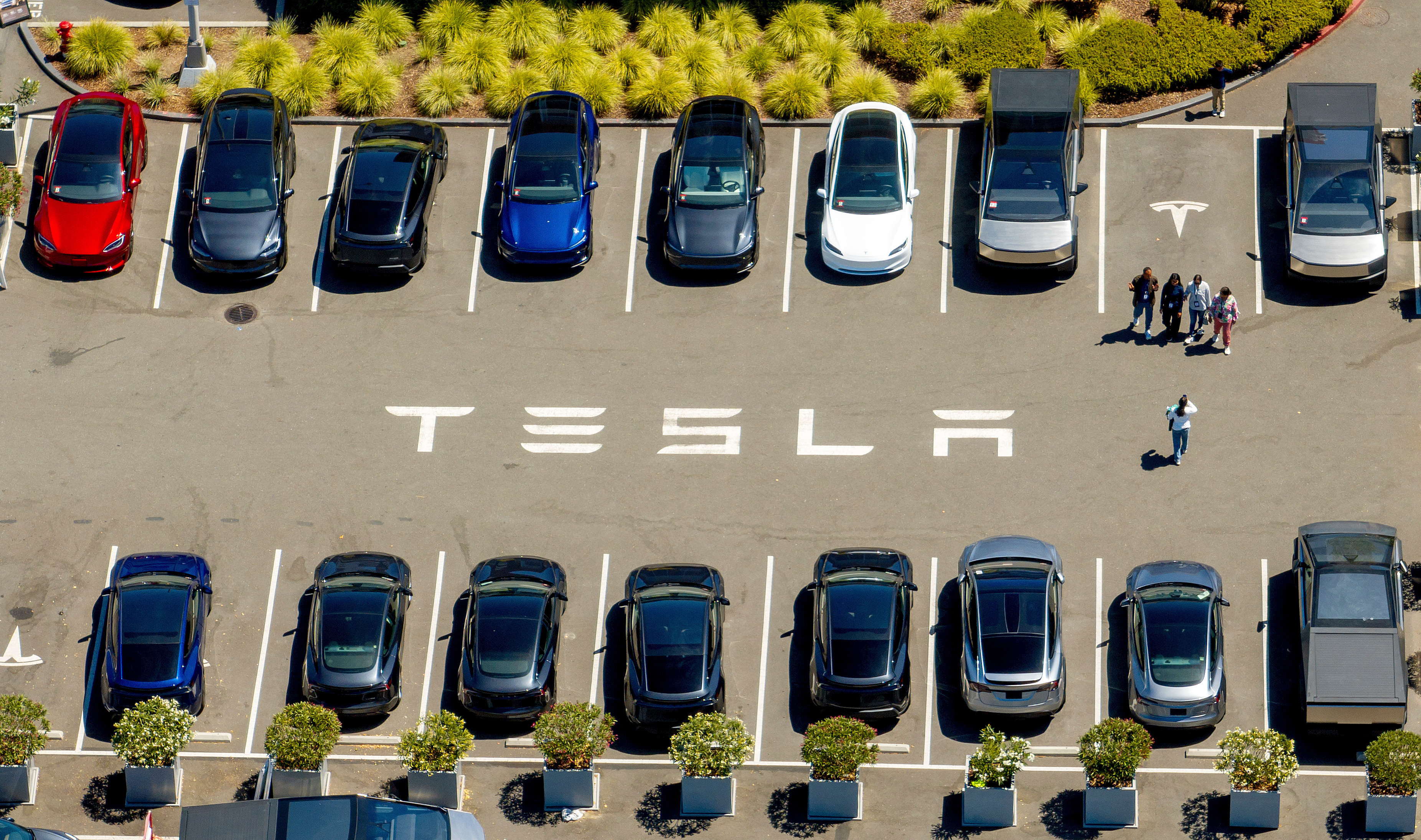 Aerial view of Tesla parking lot with multiple electric vehicles in different colors